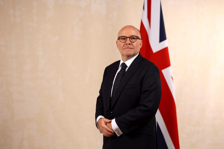 UK Attorney General Richard Hermer stands in front of a UK flag